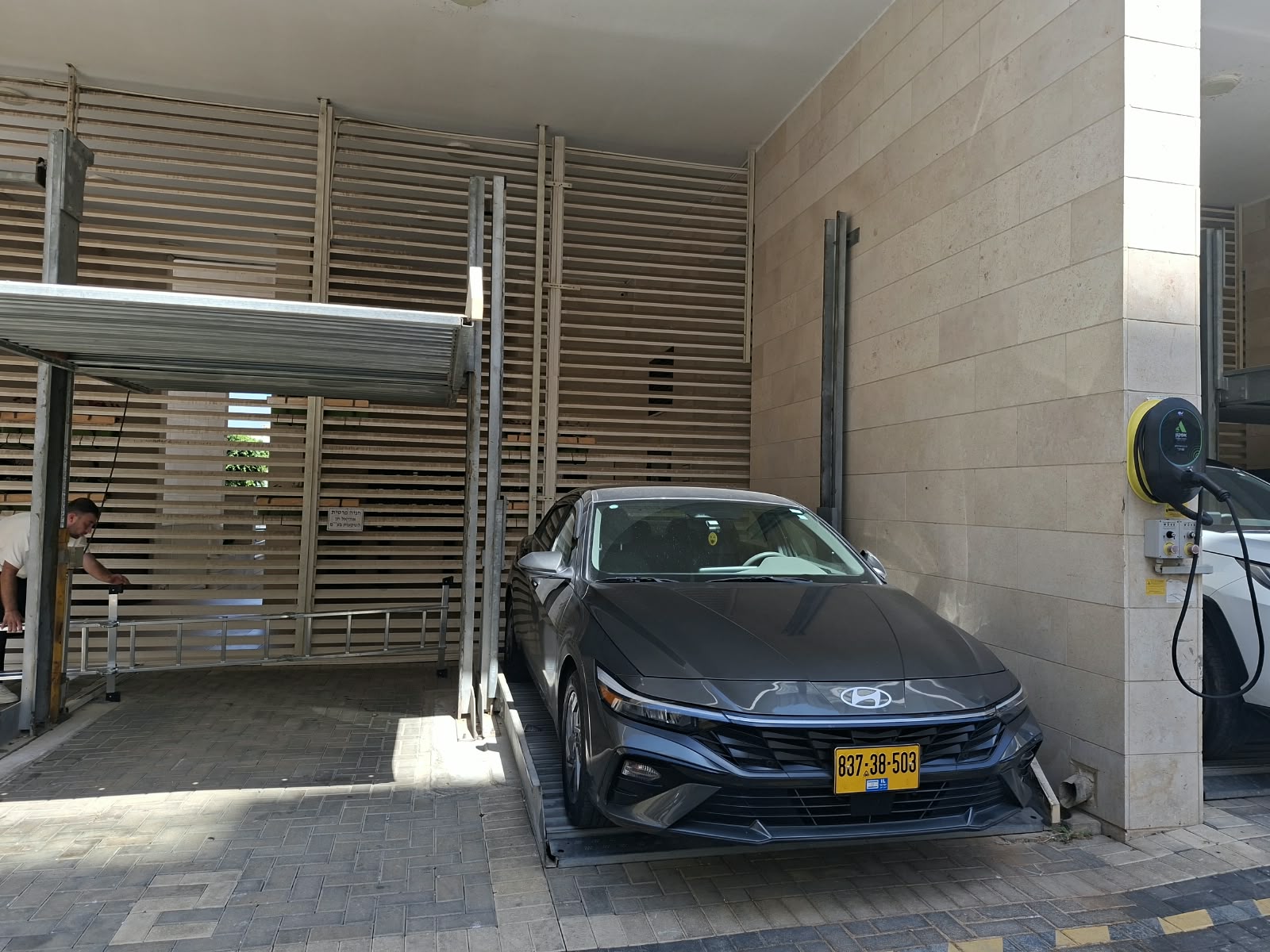 רכב שחור לצד מתקן חניה בכניסה מקורה לבניין