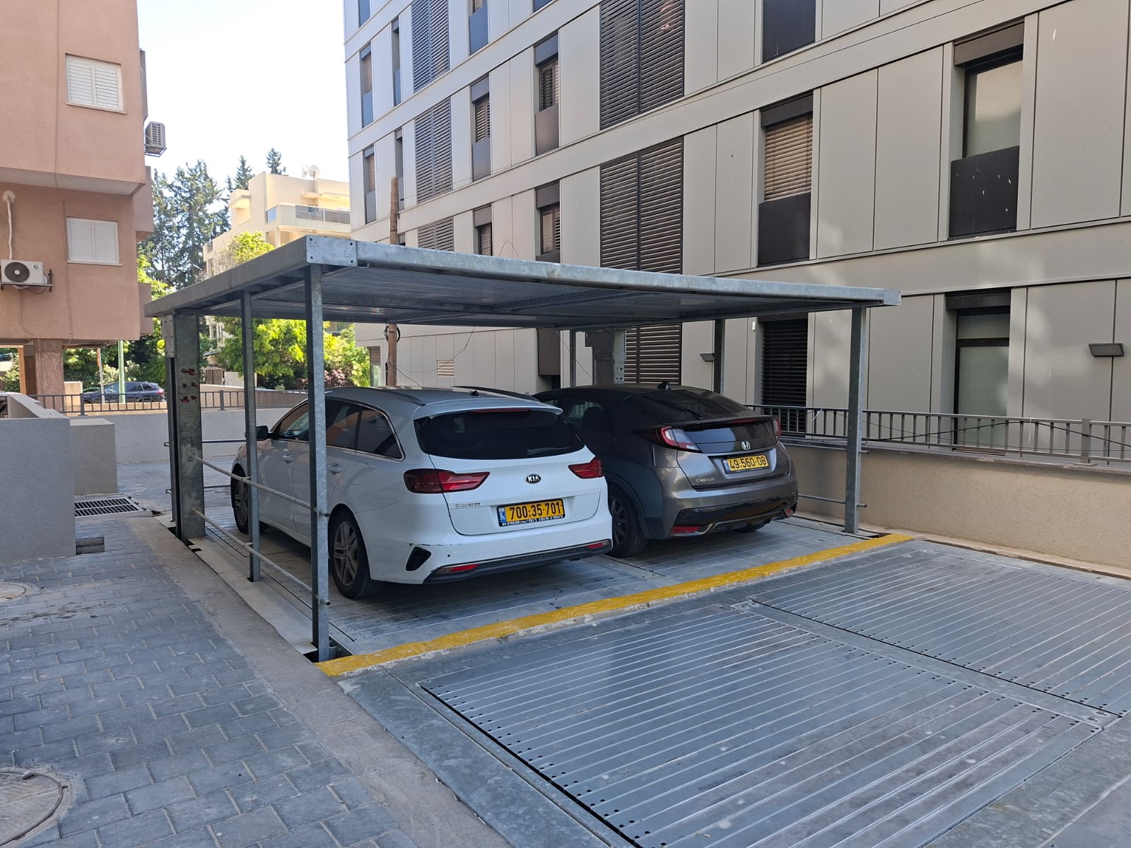 מכפיל חניה חיצוני עם שני רכבים לצד בניין מגורים