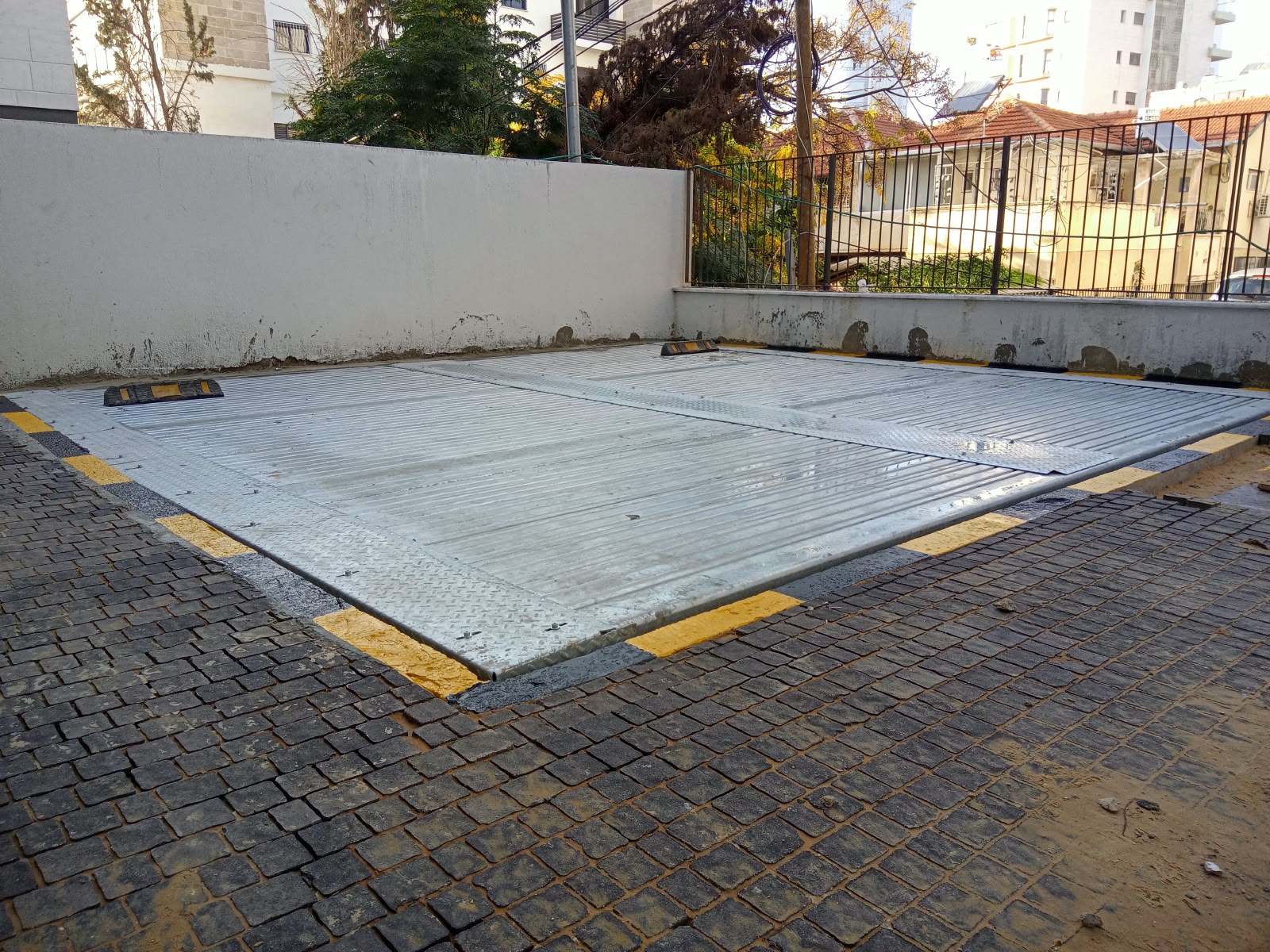 משטח חניה שקוע בגובה הרחבה לצד גדר