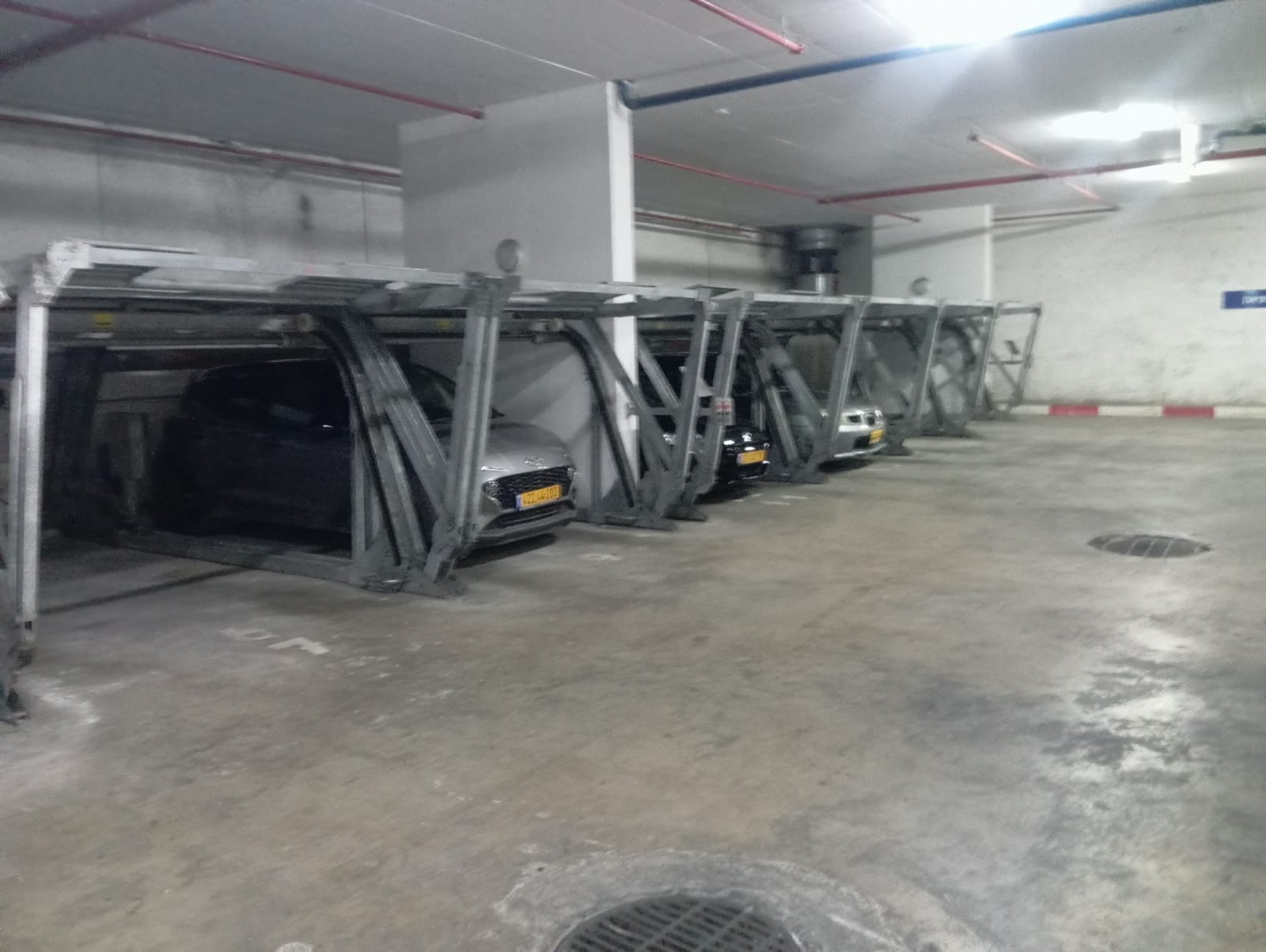שורת מתקני מכפילי חניה עם רכבים בחניון תת־קרקעי